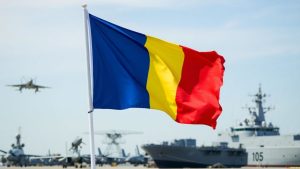Steagul României flutură lângă avioane și nave militare.