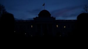 Clădirea parlamentului românesc în amurg, cu siluete.